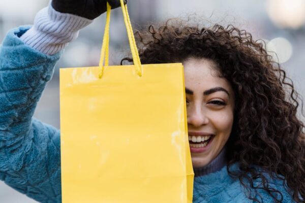 woman showing simple bright yellow gift bag and smiling