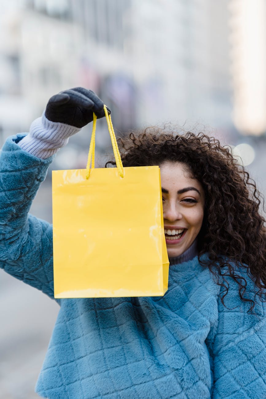 woman showing simple bright yellow gift bag and smiling