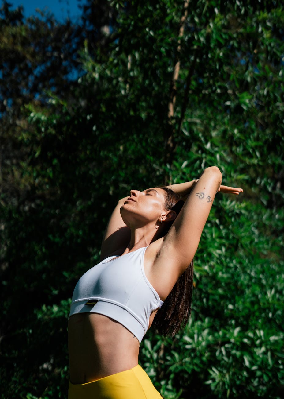 woman in white sports bra and yellow leggings stretching